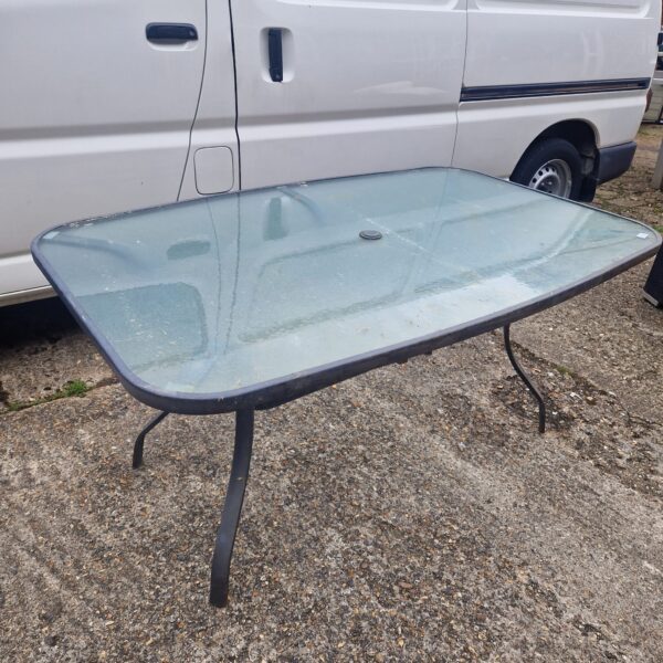 Large garden glass table with metal frame in outdoor setting.