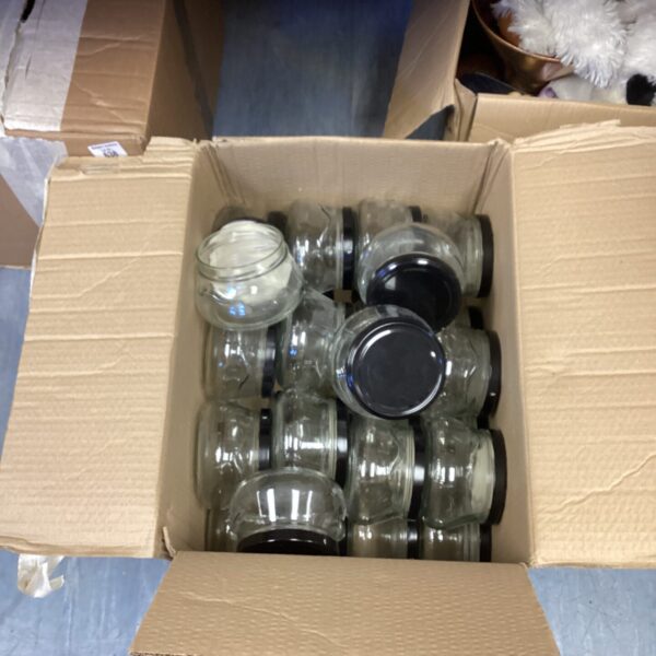 A box of clear glass storage jars with lids.