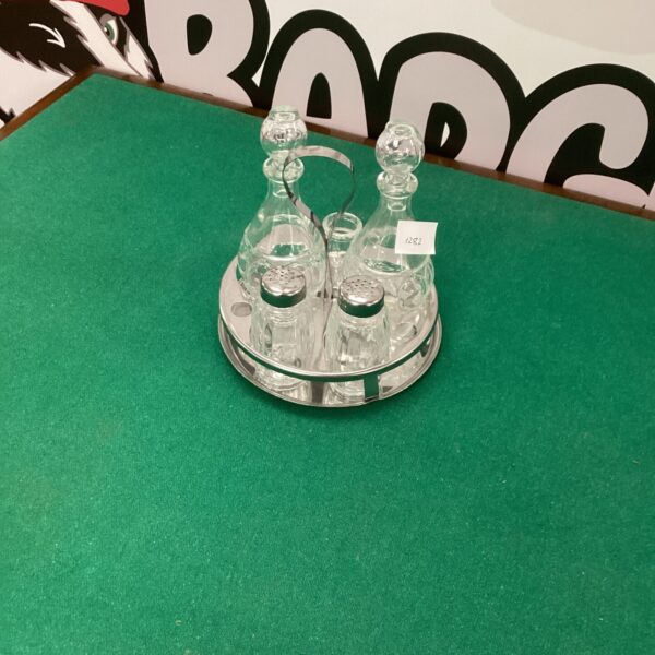 Vintage silverplate cruet set with glass bottles on tray.