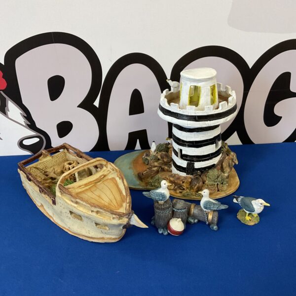 Vintage art pottery lighthouse with boat and seagull figurines for coastal decor.