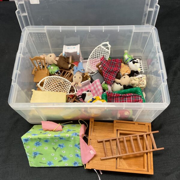 Sylvanian Families figures and accessories in a clear storage box.