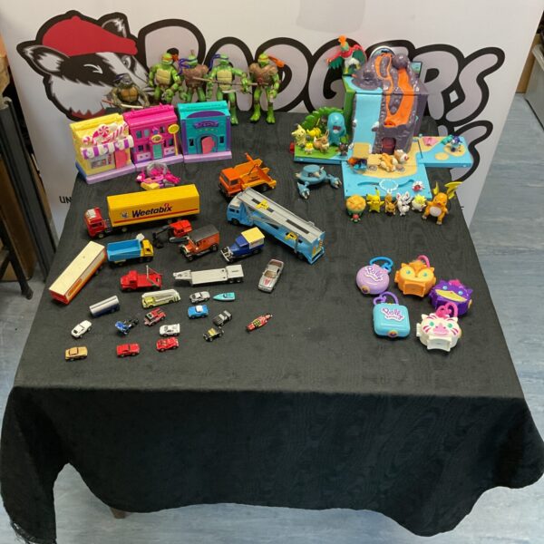 Overview of a mixed toy lot including diecast cars and Pokemon figures.