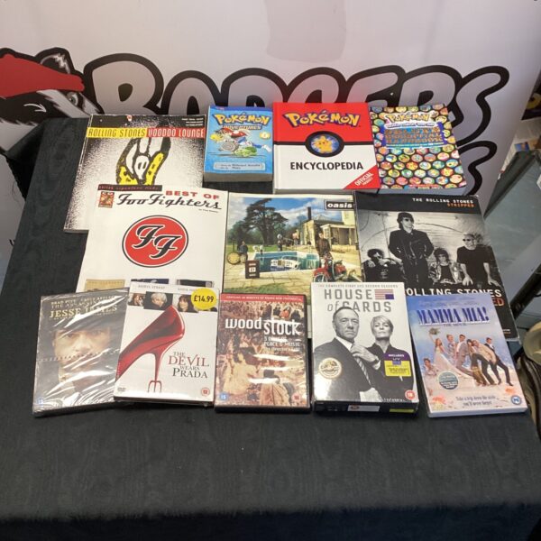 Entertainment lot featuring Oasis songbooks, Pokémon books, and DVDs.