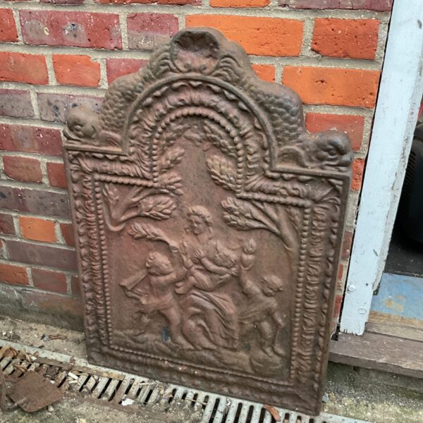 Intricate Victorian cast iron fireplace back with figures and foliage.