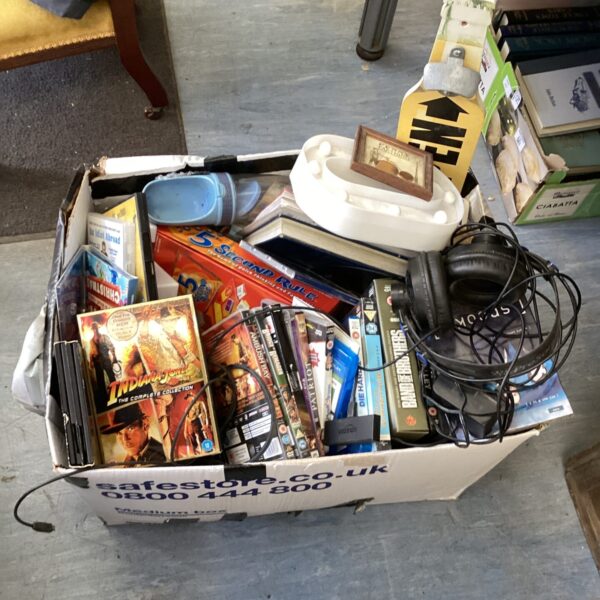 Mixed house clearance lot with DVDs, books, and VHS tapes.