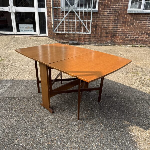 Vintage gate leg table unfolded, showing light oak veneer.