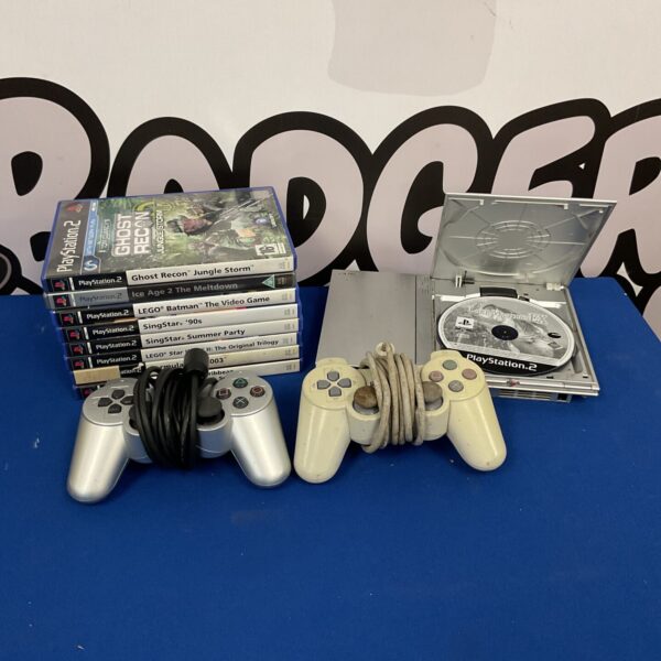 Silver PlayStation 2 Slim console with games and controllers.