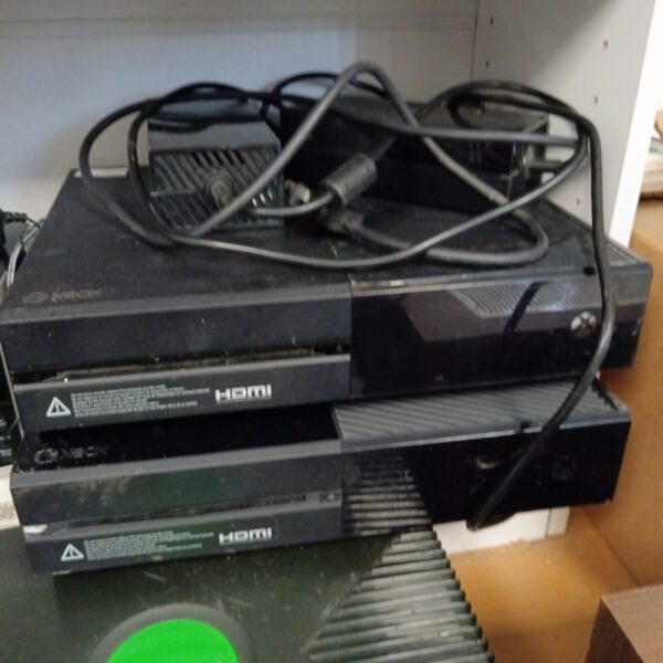 Pair of black Xbox One gaming consoles with cables.