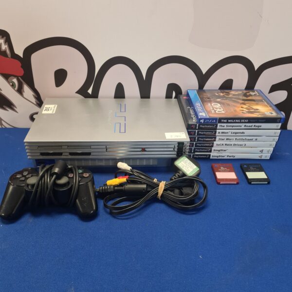 Silver PlayStation 2 console with games and controller.