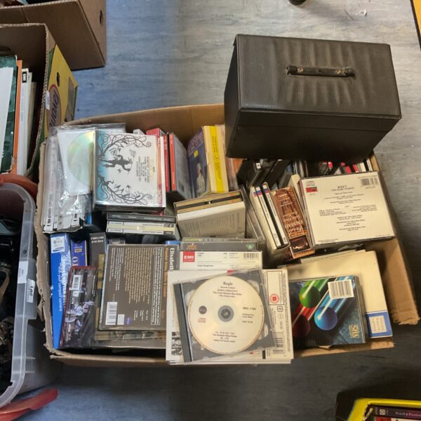 Overview of a mixed media lot including CDs, VHS tapes, and DVDs.