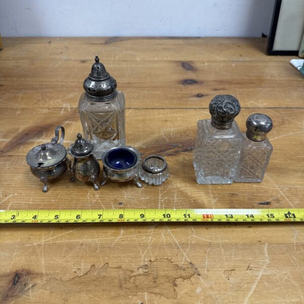 Full view of antique silver plated cruet set on wooden surface.