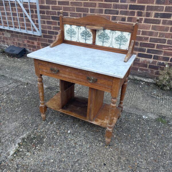 Victorian wash stand with marble top and decorative tile backsplash.