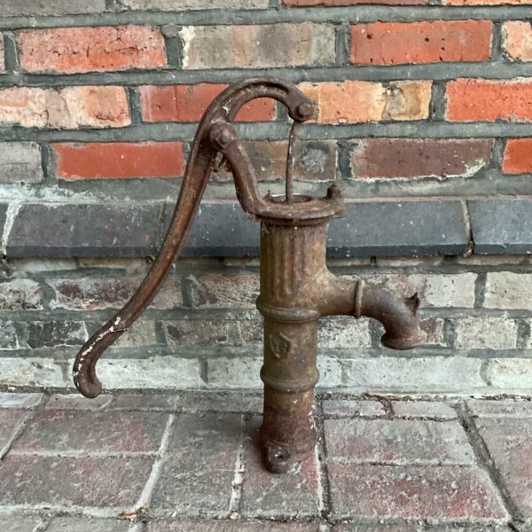 Vintage cast iron garden pump with curved handle.
