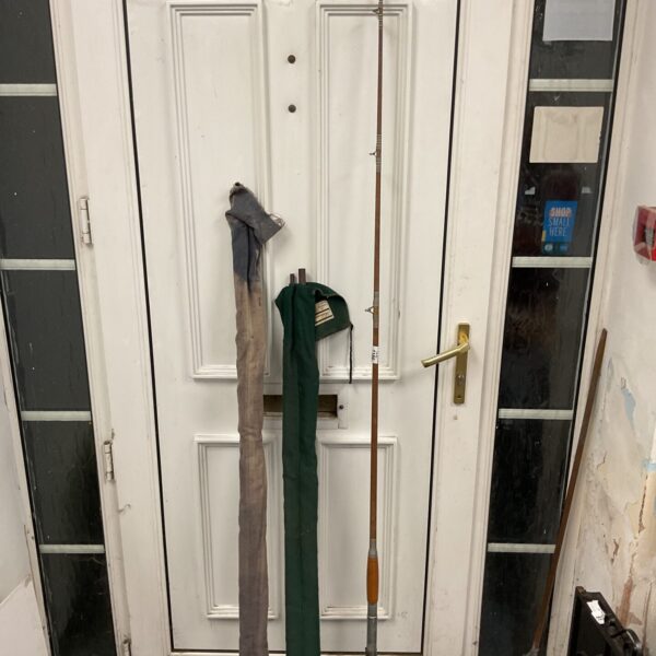 Three vintage fishing rods leaning against a wall.