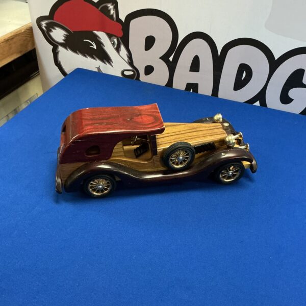 Detailed wooden model of a vintage car on display.