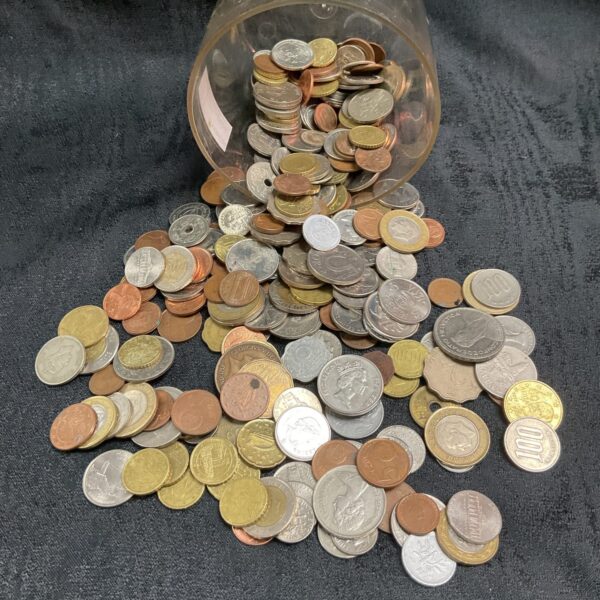 Jar filled with assorted coins, including British and foreign currency.