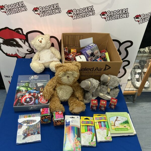 Mixed toy lot in a cardboard box with action figures and teddy bear.