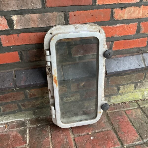 Vintage boat porthole against a brick wall.