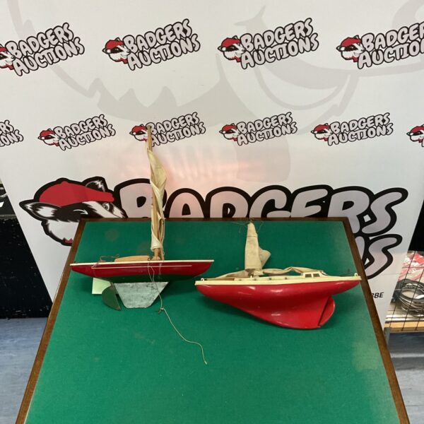 Pair of vintage pond yachts with wooden hulls and cloth sails.