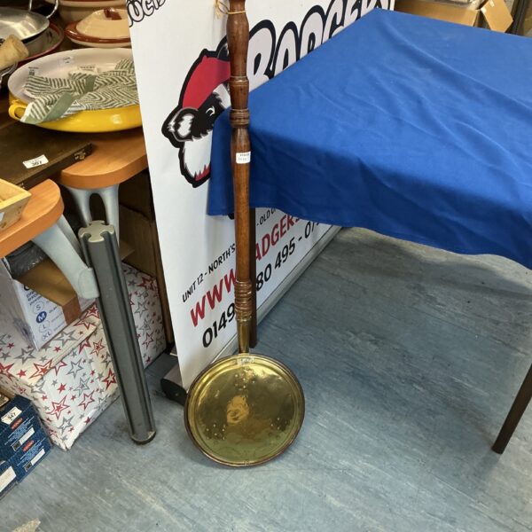 Antique brass bed warmer with wooden handle, side view.