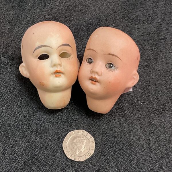 Two antique German bisque doll heads with painted features.