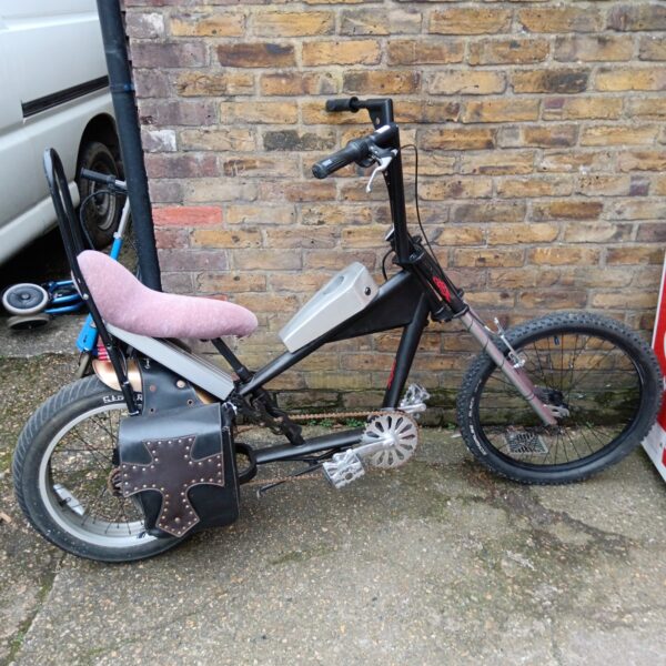 Side view of a striking gothic chopper bike with electric motor.