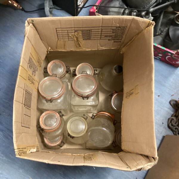 Vintage Kilner jars stacked in a cardboard box, ideal for preserving.