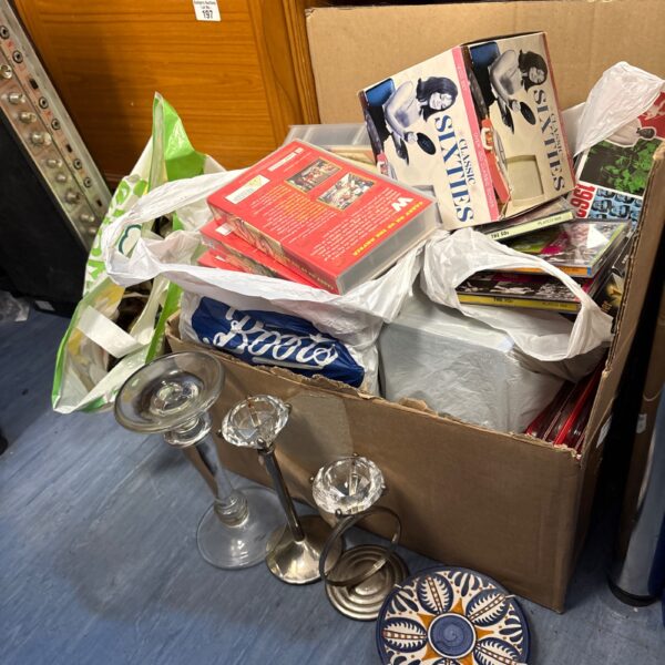 Mixed lot of VHS tapes, CDs, and ornaments on display.