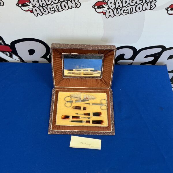 Open vintage manicure set with silver tools inside a lined case.