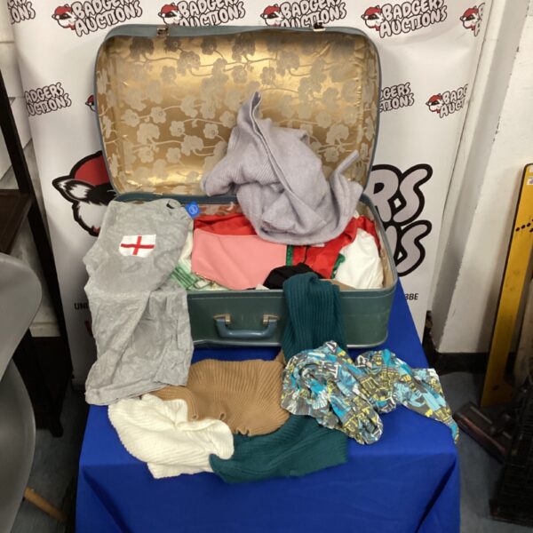 Vintage suitcase filled with assorted clothing and retro fashion items.