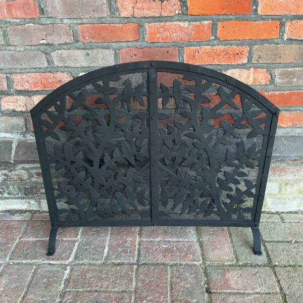 Antique metal firescreen with bird and vine design for fireplace safety.