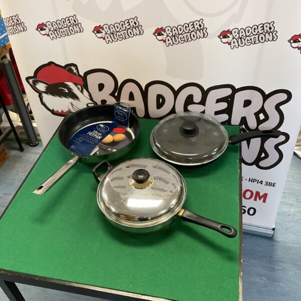 Three frying pans with Pyrex and steel lids, kitchen cookware set.