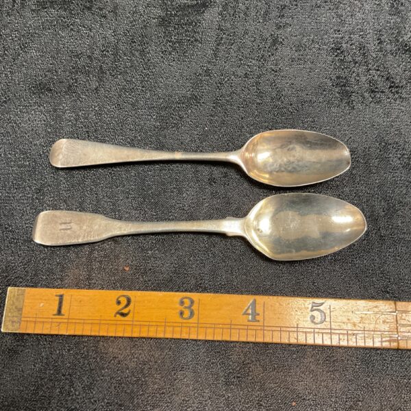Antique Georgian silver teaspoons displayed with a ruler for scale.