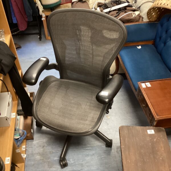 Black Herman Miller office chair with mesh back and adjustable arms.