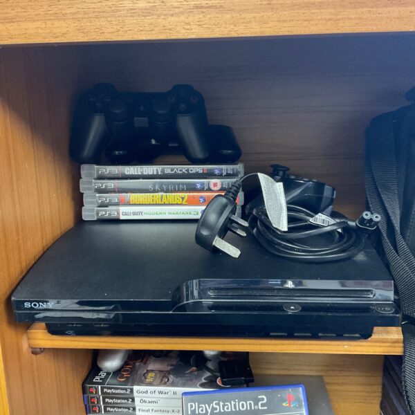 Sony PlayStation 3 Slim console with controllers and games.