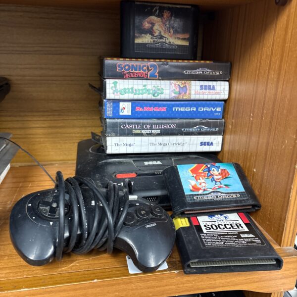Sega Mega Drive console with controller and game cartridges.