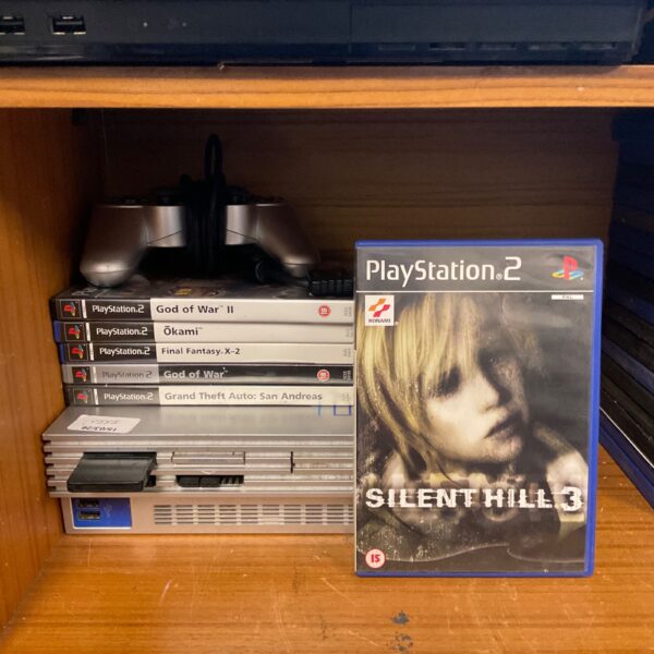 Silver Sony PlayStation 2 console with games, including Final Fantasy and Silent Hill 3.