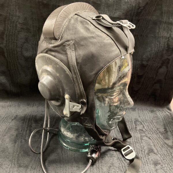 Vintage Soviet pilot helmet displayed on a stand, side view.